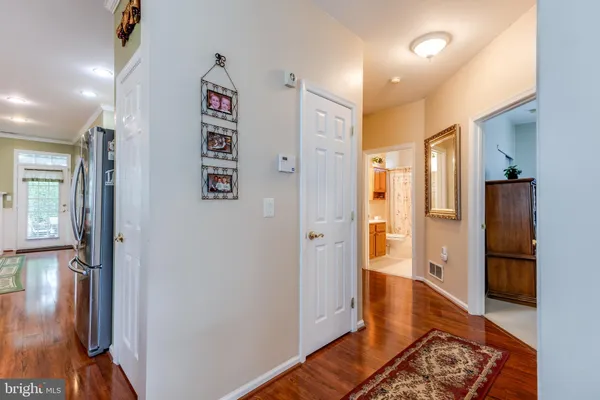 a view of a hallway with wooden floor and a bathroom