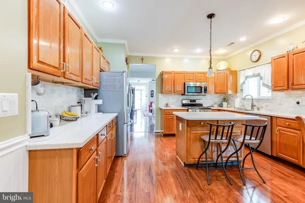 a kitchen with stainless steel appliances granite countertop a refrigerator a sink a stove and a wooden floors