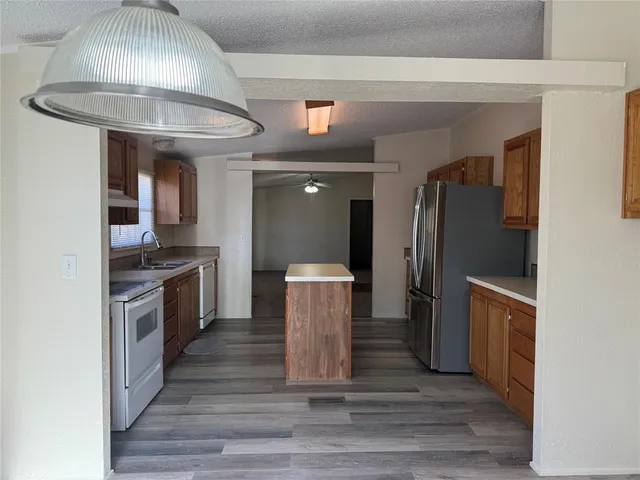 a kitchen with stainless steel appliances granite countertop a refrigerator a stove and a wooden floors