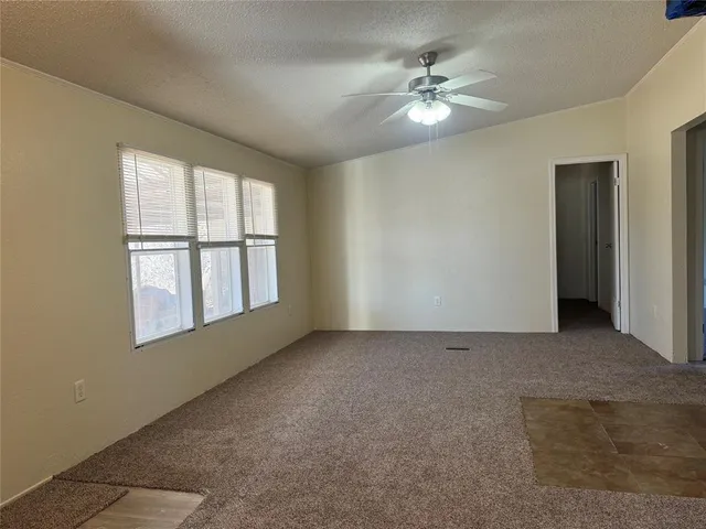an empty room with windows and chandelier fan