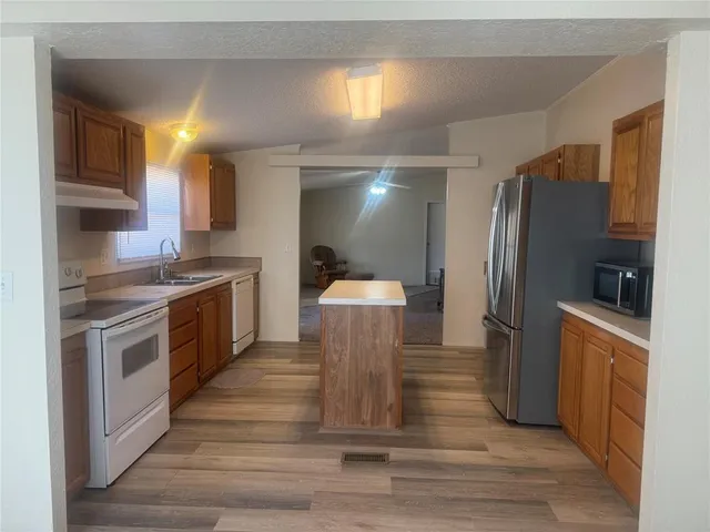 a kitchen with stainless steel appliances granite countertop a refrigerator a stove and a sink