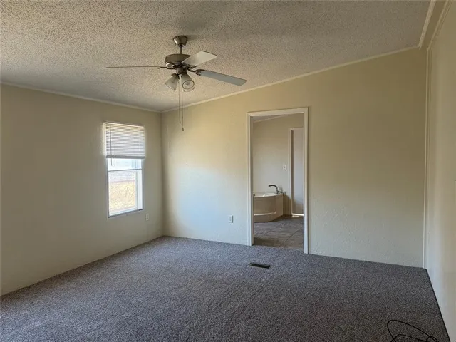 an empty room with a chandelier fan and windows