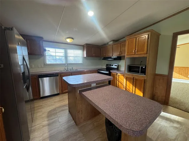 a kitchen with stainless steel appliances granite countertop a sink a stove a refrigerator cabinets and a dining table