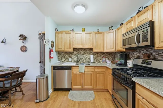 a kitchen with stainless steel appliances granite countertop a stove a sink dishwasher and microwave with wooden floor