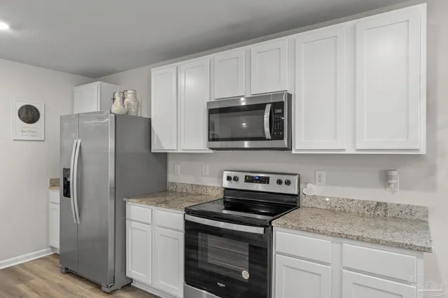 a kitchen with stainless steel appliances granite countertop white cabinets granite counter tops and a stove