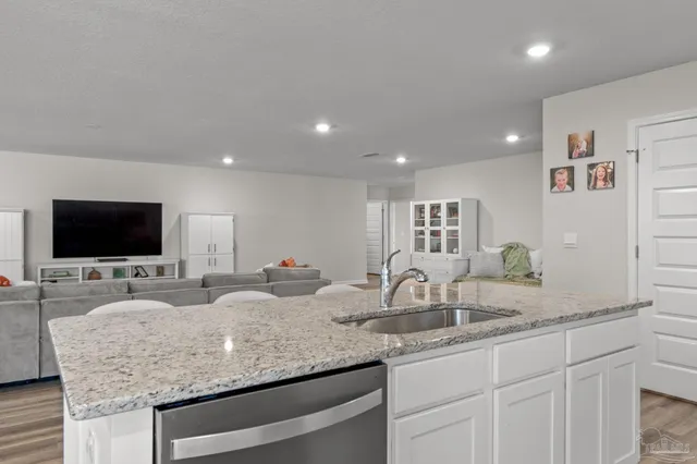 a kitchen with granite countertop a sink and a flat screen tv