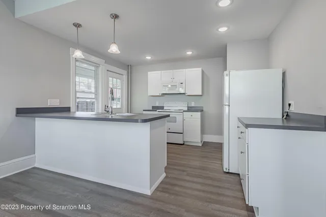 a kitchen with stainless steel appliances granite countertop a sink a stove a refrigerator and island with wooden floor