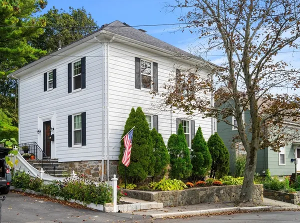 a front view of a house with a yard and potted plants