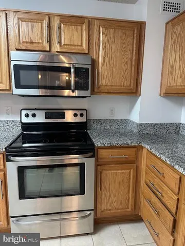 a kitchen with granite countertop a stove microwave and sink
