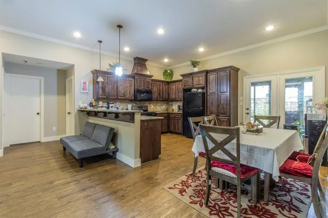 a kitchen with stainless steel appliances kitchen island granite countertop a stove a sink dishwasher a dining table and chairs with wooden floor