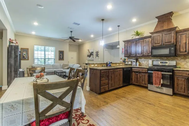 a kitchen with stainless steel appliances kitchen island granite countertop a stove a sink a refrigerator and chairs