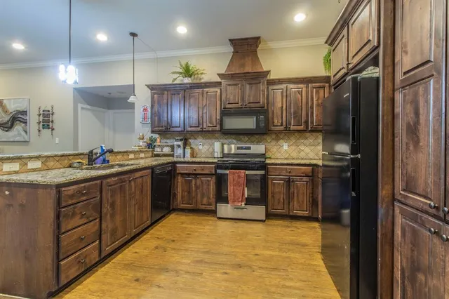 a kitchen with stainless steel appliances granite countertop a sink refrigerator and cabinets