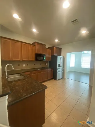 a kitchen with stainless steel appliances granite countertop a refrigerator a stove a sink and a microwave