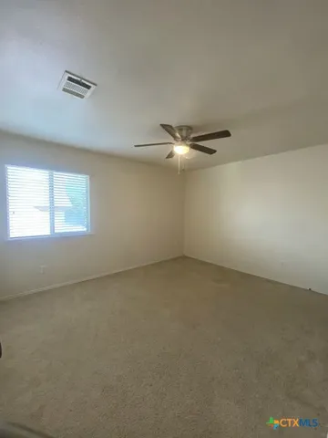a view of an empty room and chandelier fan
