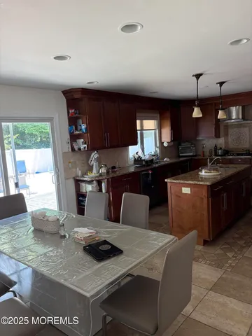 a kitchen with a stove a sink a kitchen island with chairs and wooden cabinets