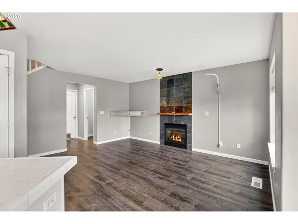 a view of an empty room with wooden floor and a fireplace