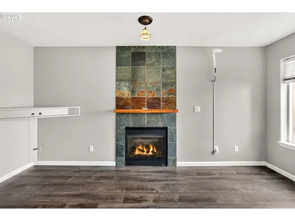 a view of an empty room with wooden floor and a fireplace