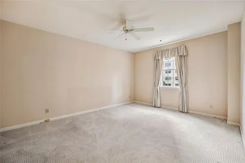 an empty room with windows and ceiling fan