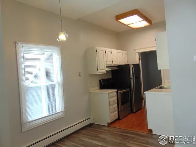 an empty room with windows and refrigerator