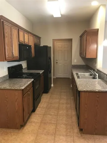 a kitchen with granite countertop a refrigerator and a stove top oven