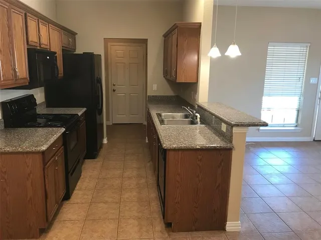 a kitchen with granite countertop a refrigerator a stove and a sink