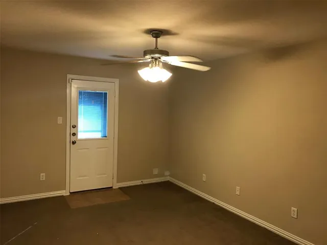 an empty room with a chandelier fan and wooden floor