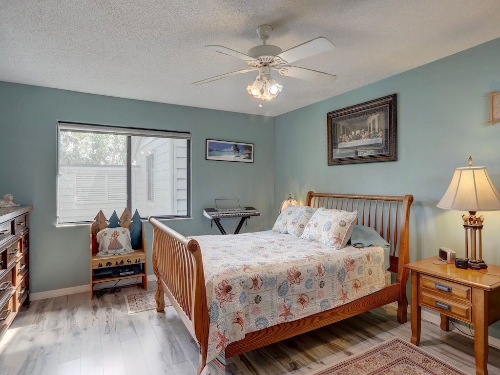2150 Pine Creek Boulevard, Unit 202 Vero Beach, FL 32966 - Photo 16 of 31 a bedroom with a bed and a chandelier