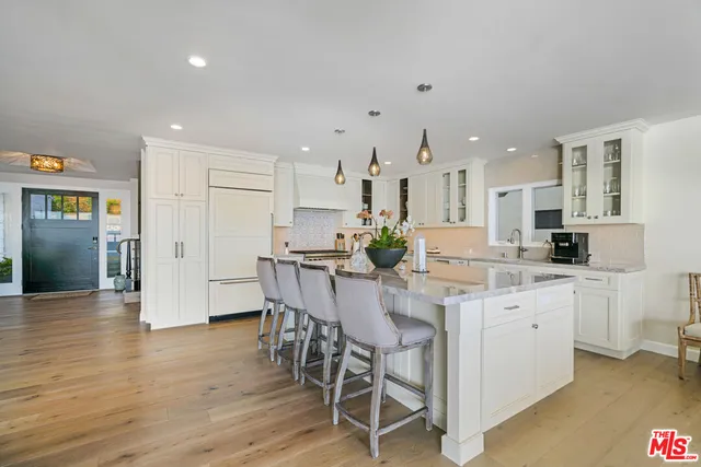 a kitchen with stainless steel appliances kitchen island granite countertop a dining table chairs and white cabinets