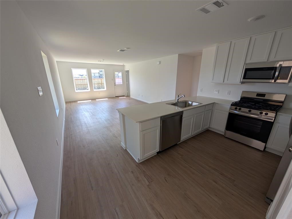 654 Maria Elena Way Cleveland, TX 77327 - Photo 7 of 23 a kitchen with stainless steel appliances a stove top oven a sink and wooden floors