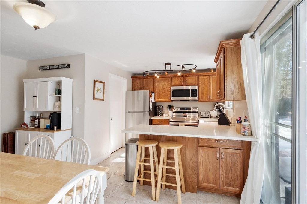 75 Sandy Pond Road, Unit 41 Ayer, MA 01432 - Photo 13 of 36 a kitchen with stainless steel appliances kitchen island granite countertop a refrigerator a stove a sink dishwasher and white cabinets with wooden floor