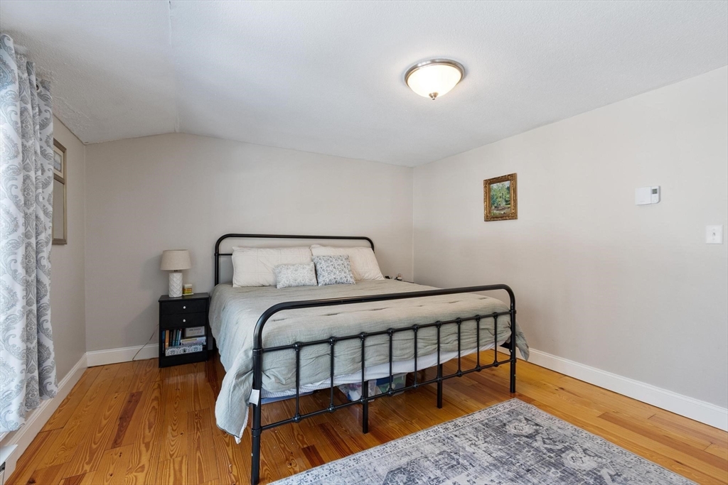 75 Sandy Pond Road, Unit 41 Ayer, MA 01432 - Photo 25 of 36 a bedroom with a bed and wooden floor