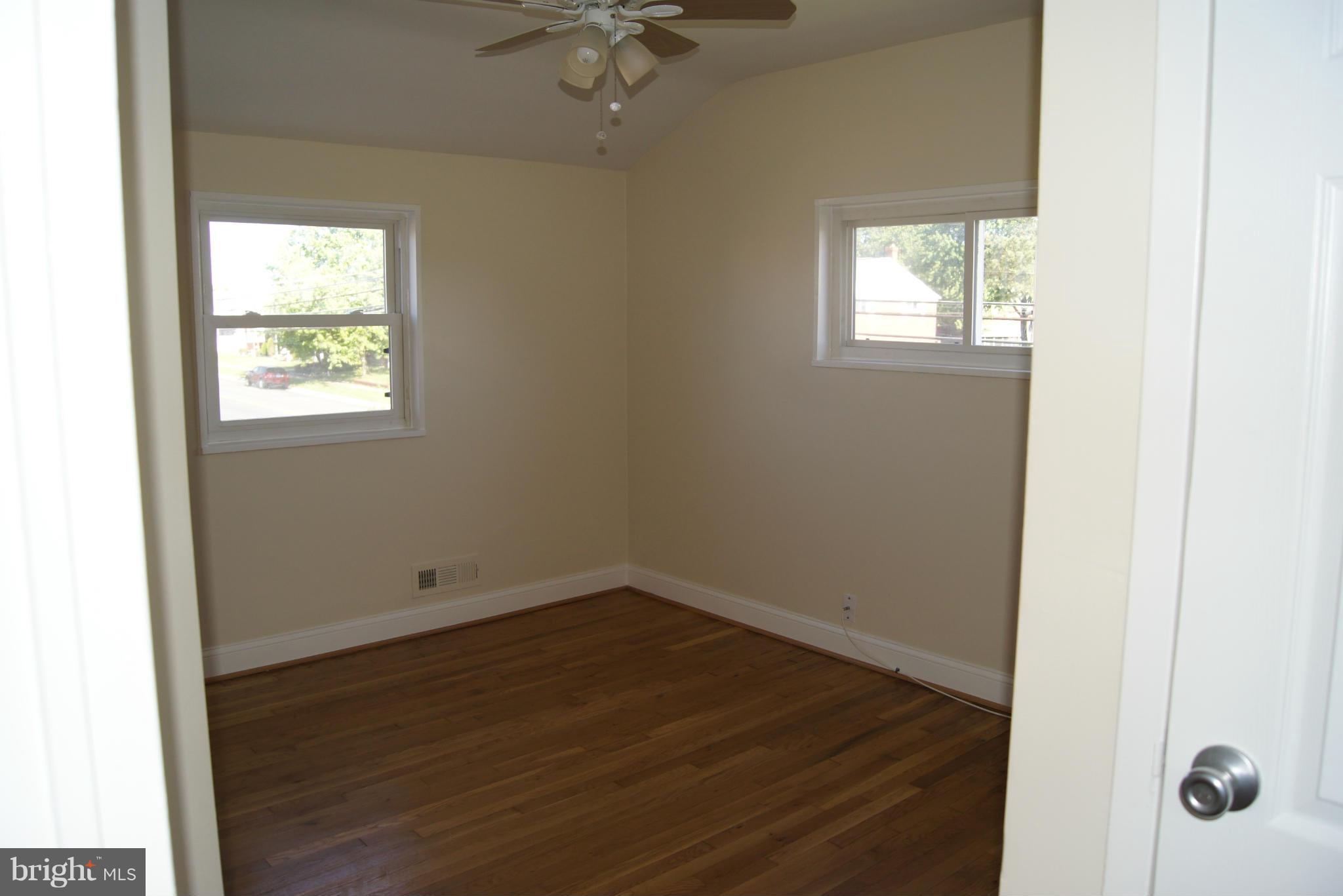 7954 Charlesmont Road Baltimore, MD 21222 - Photo 11 of 24 an empty room with wooden floor and windows