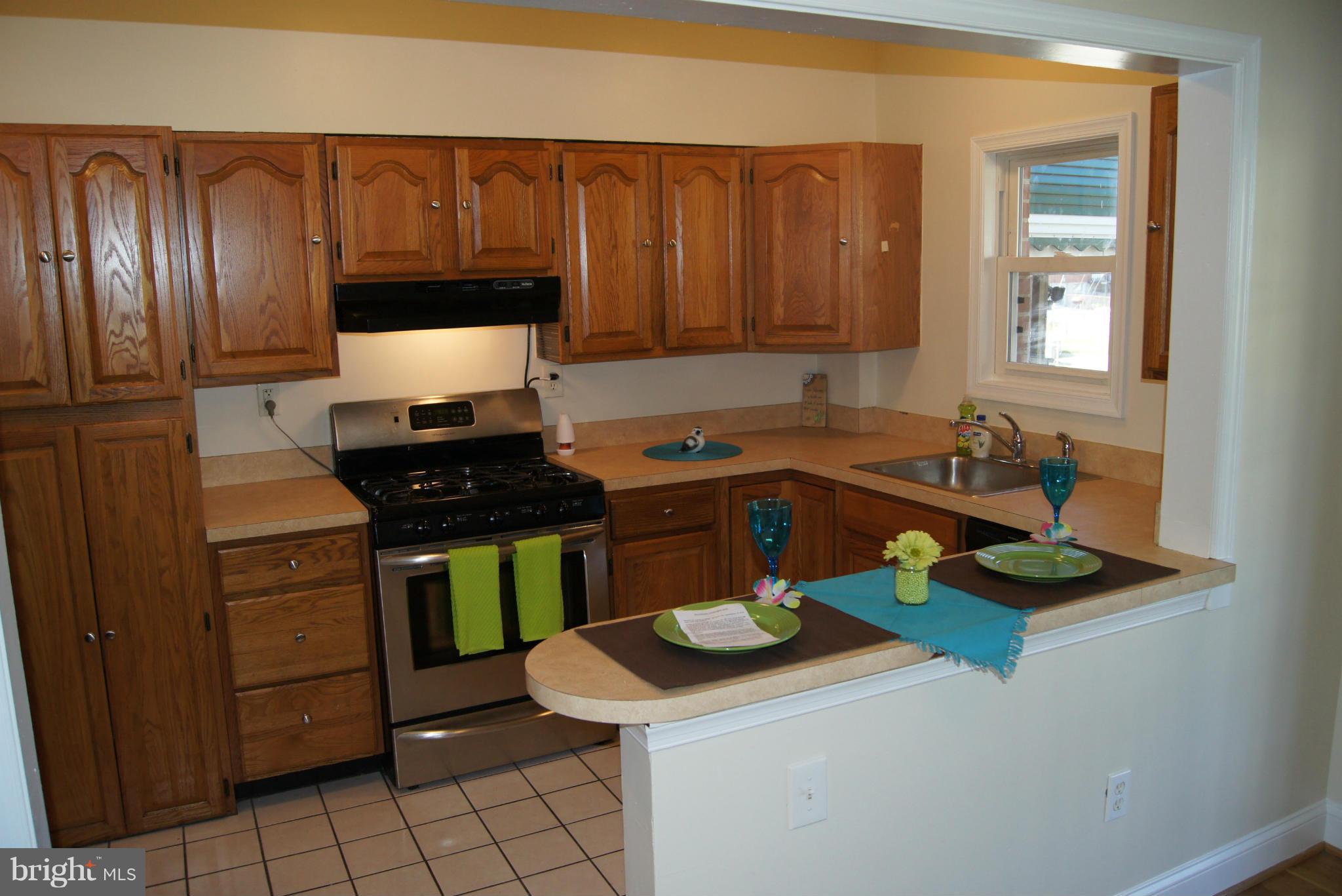 7954 Charlesmont Road Baltimore, MD 21222 - Photo 5 of 24 a kitchen with a sink a stove cabinets and a counter top space