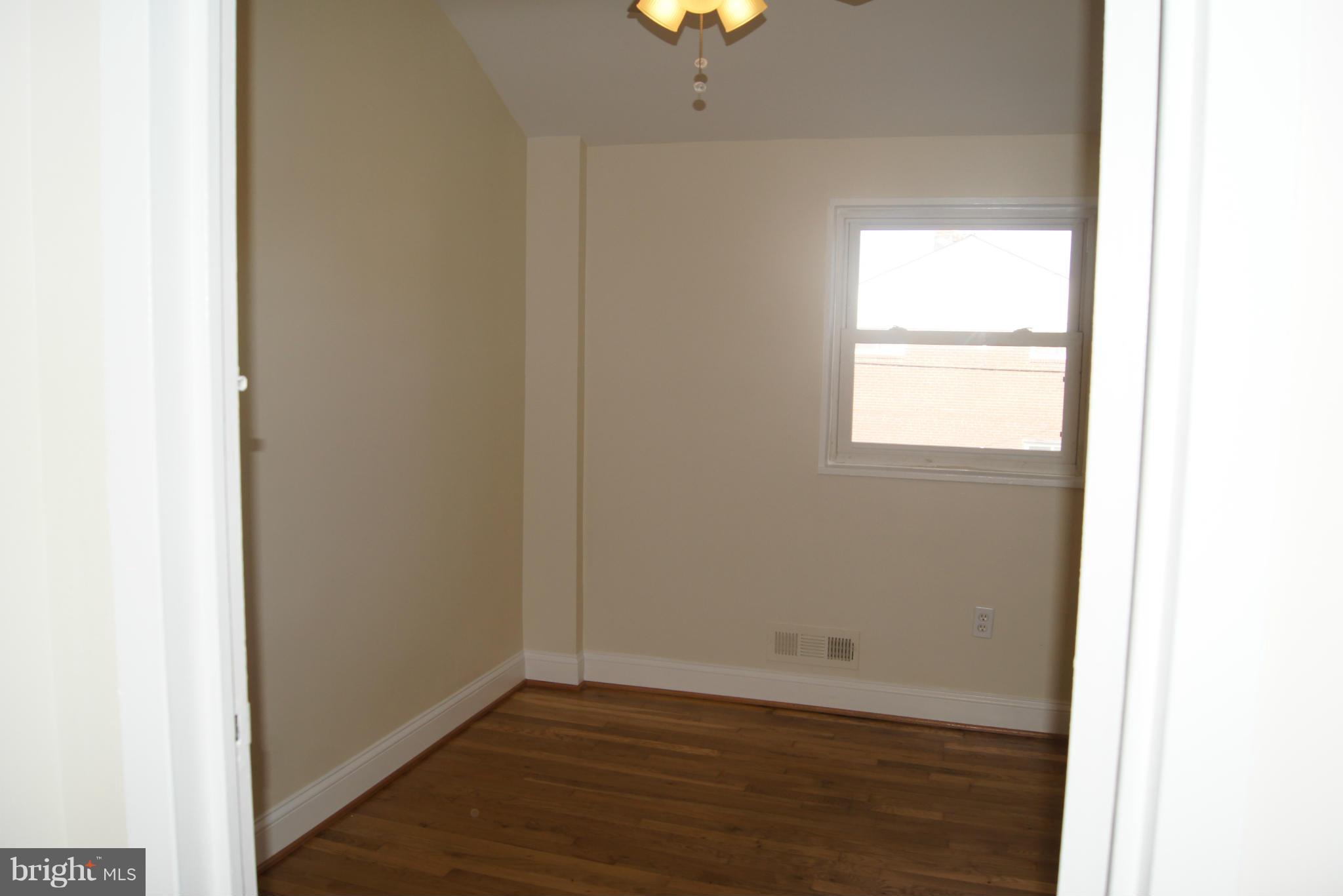 7954 Charlesmont Road Baltimore, MD 21222 - Photo 10 of 24 a view of an empty room with wooden floor and a window