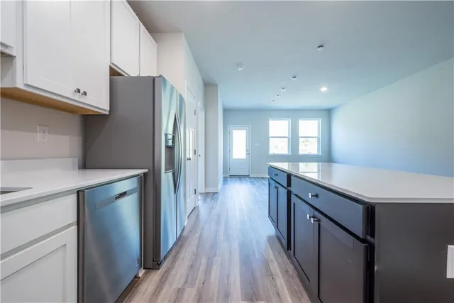 a kitchen with granite countertop a refrigerator a sink and wooden floors