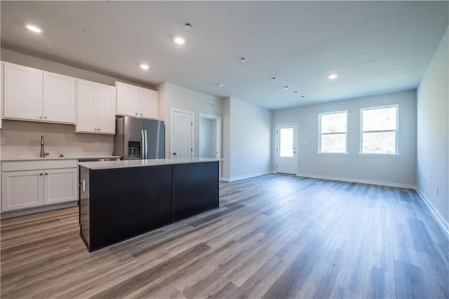 a kitchen with stainless steel appliances granite countertop a refrigerator a sink dishwasher a stove and white countertops with wooden floor