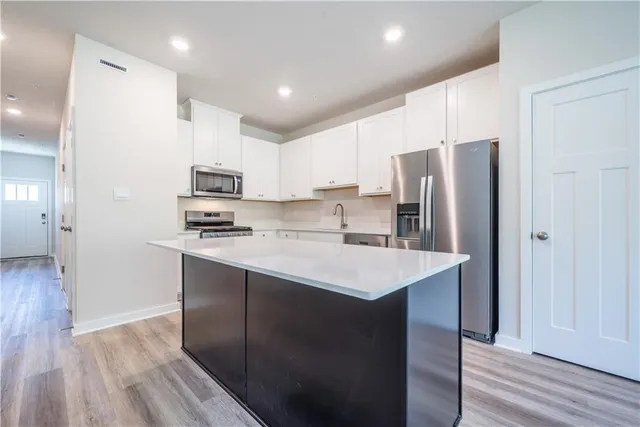 a kitchen with kitchen island white cabinets and stainless steel appliances