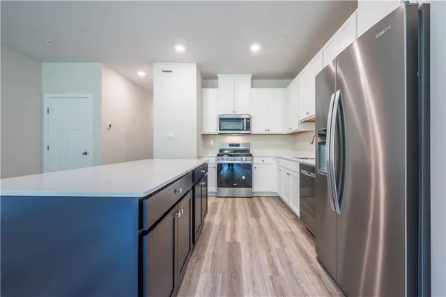 a kitchen with kitchen island white cabinets appliances and wooden floor