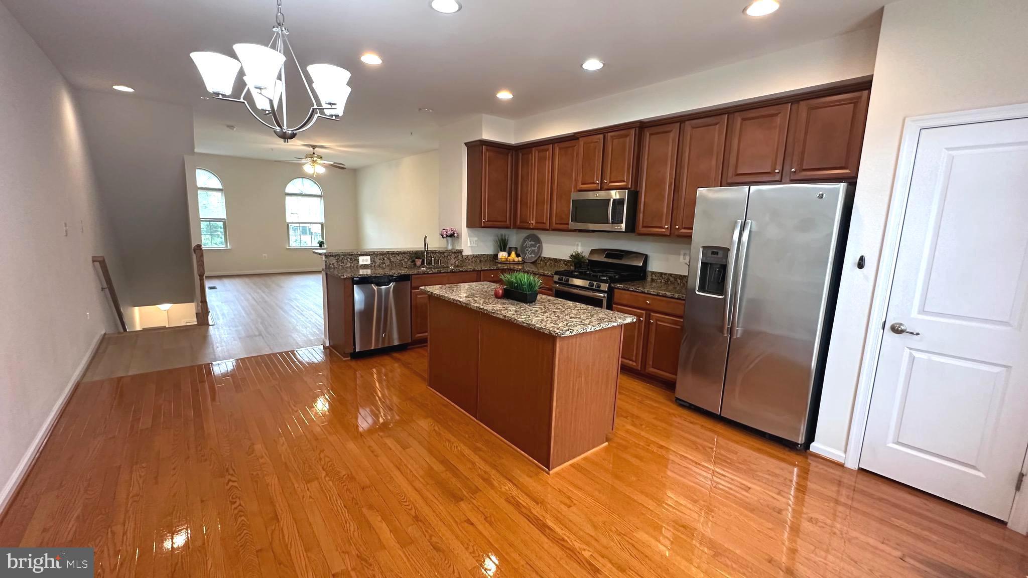 7343 Old Calvary Road Hanover, MD 21076 - Photo 2 of 35 a kitchen with stainless steel appliances granite countertop a refrigerator a sink dishwasher a stove and white countertops with wooden floor