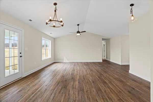 a view of a room with wooden floor chandelier and windows