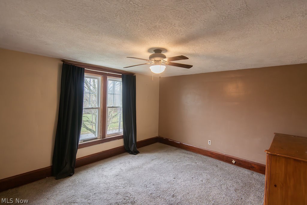 1195 South Johnson Road Sebring, OH 44672 - Photo 16 of 34 Unfurnished room featuring ceiling fan, a textured ceiling, and carpet