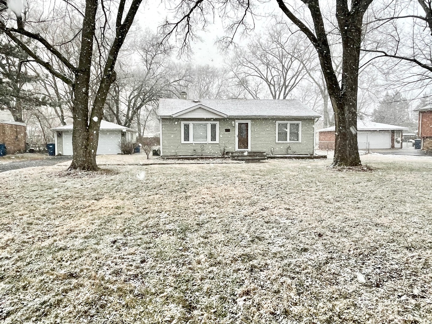 a front view of a house with a yard covered in snow