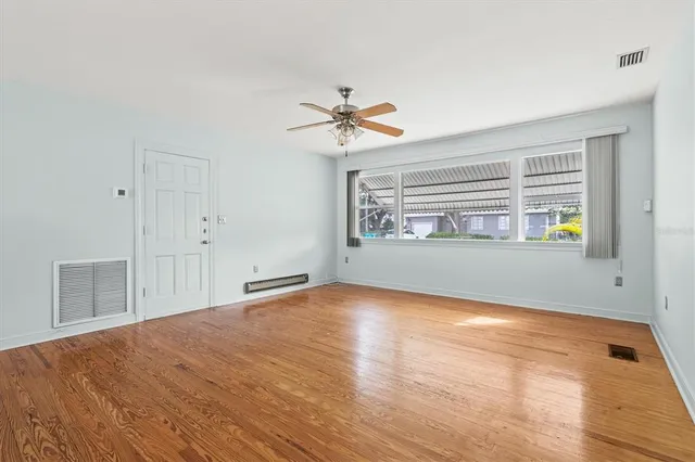a view of empty room with wooden floor and window