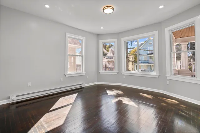 a view of an empty room with a window and wooden floor