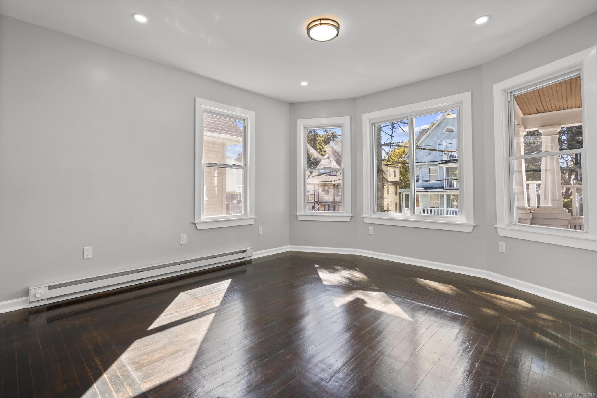 230 Cooke Street, Unit 2 Waterbury, CT 06710 - Photo 3 of 16 a view of an empty room with a window and wooden floor