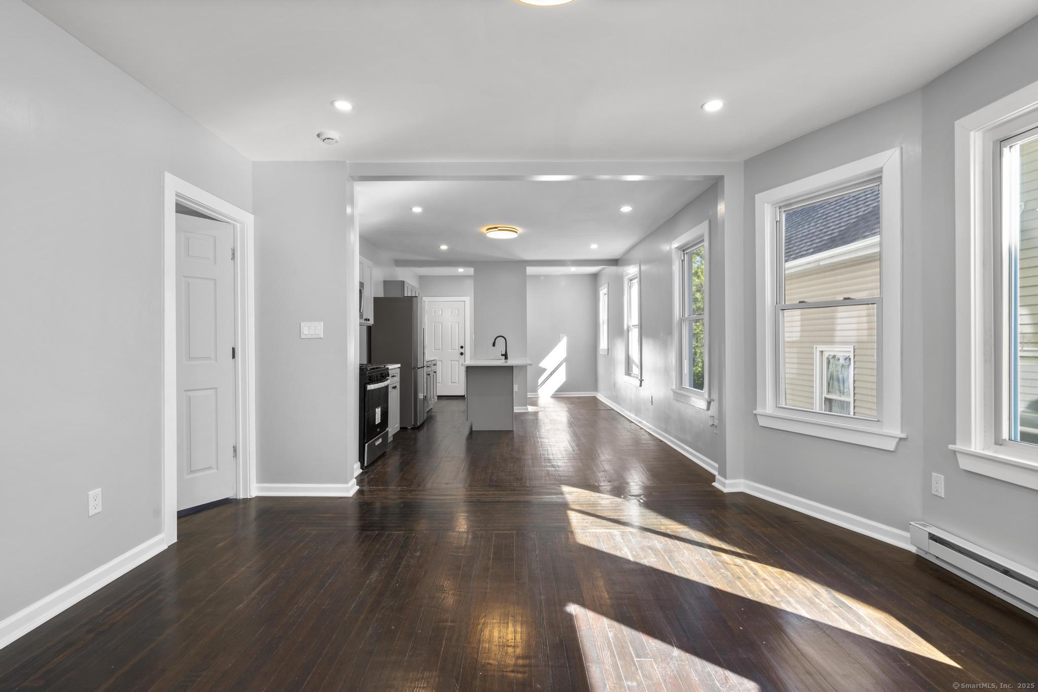 230 Cooke Street, Unit 2 Waterbury, CT 06710 - Photo 4 of 16 a view of a hallway with wooden floor windows and a kitchen
