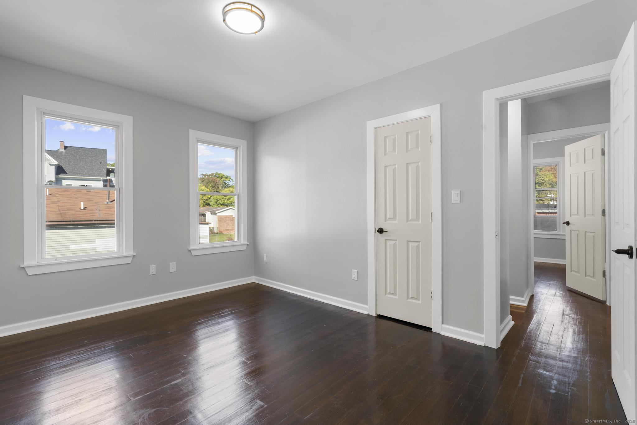 230 Cooke Street, Unit 2 Waterbury, CT 06710 - Photo 8 of 16 an empty room with wooden floor and windows
