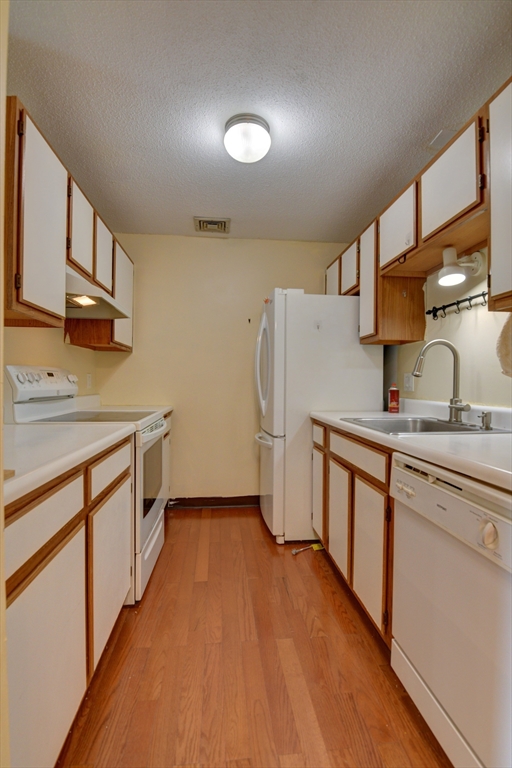 15 Bower Road, Unit A11 Quincy, MA 02169 - Photo 11 of 29 a kitchen with stainless steel appliances granite countertop a stove a sink dishwasher and a refrigerator with wooden floor