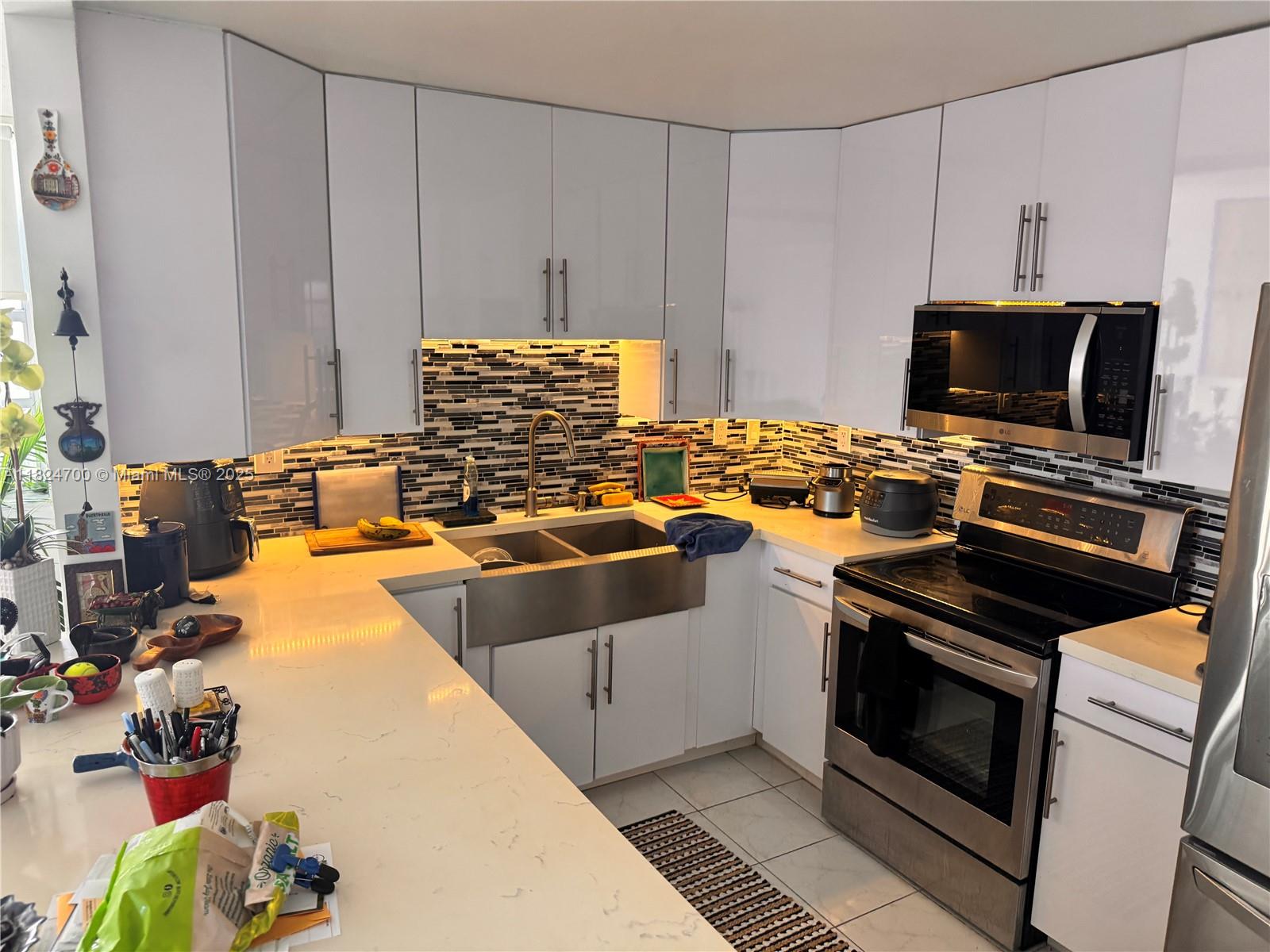2750 Northeast 183rd Street, Unit 2103 Aventura, FL 33160 - Photo 5 of 30 a kitchen with stainless steel appliances a stove a sink and a microwave