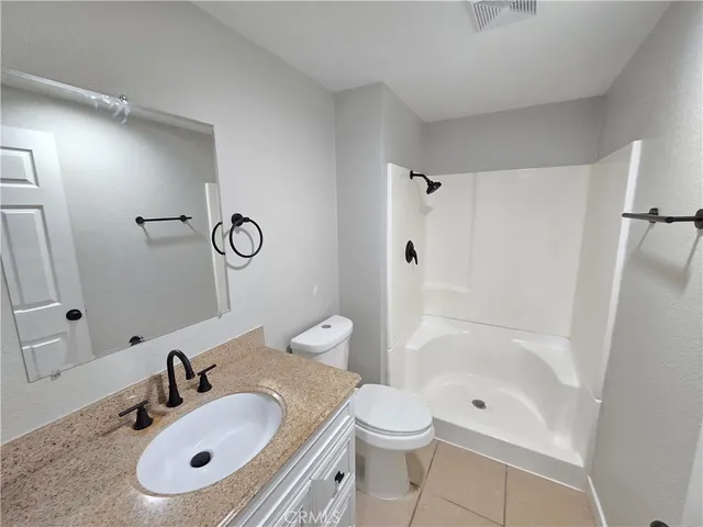 a view of an empty room with wooden floor and a ceiling fan